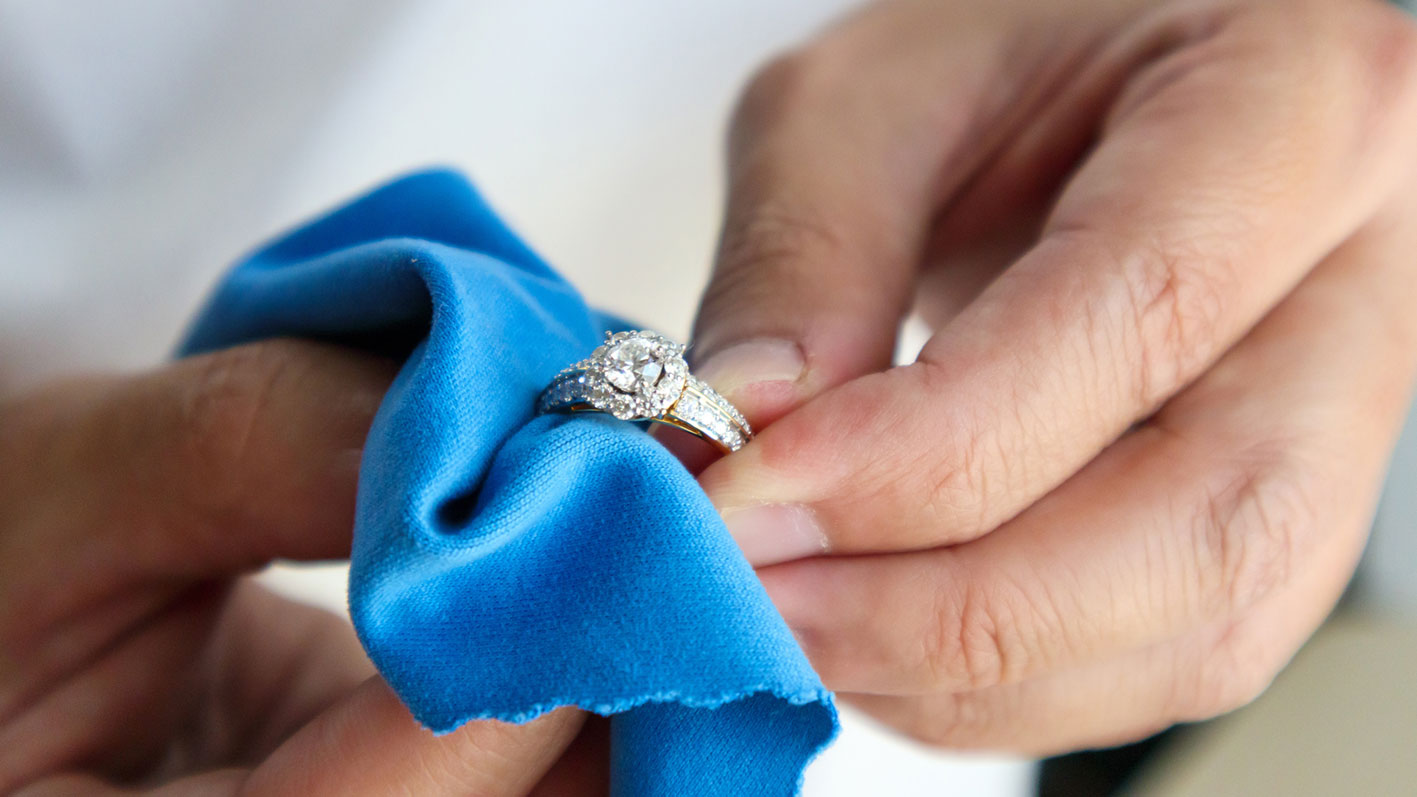 Der Juwelier poliert den Diamantring mit einem Poliertuch.