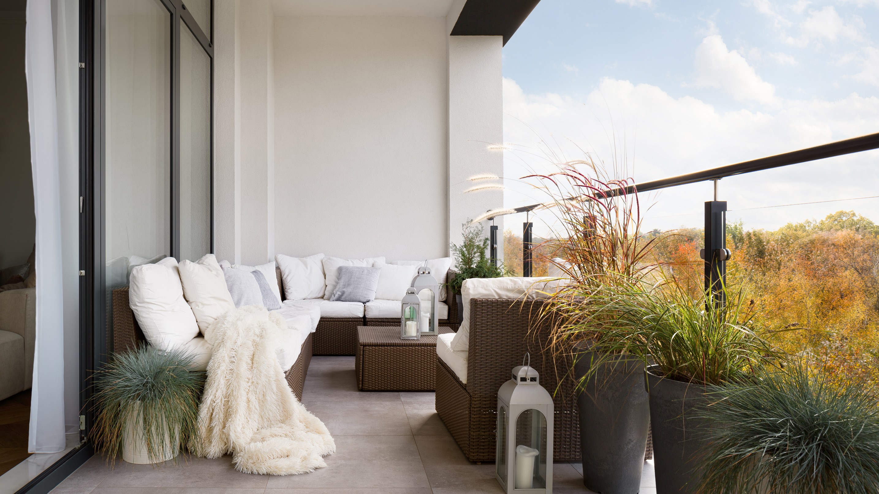 Modern gestalteter Balkon mit Glasgeländer und wetterfestem Gartensofa 