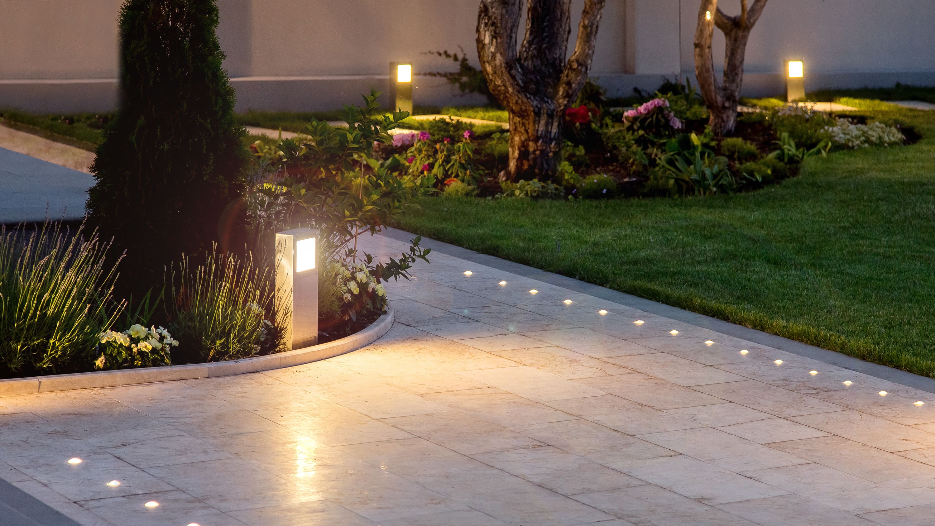 Modern gestaltete Terrasse, funktional sowie ästhetisch beleuchtet mit Lichterketten, Lampen und Kerzen. 