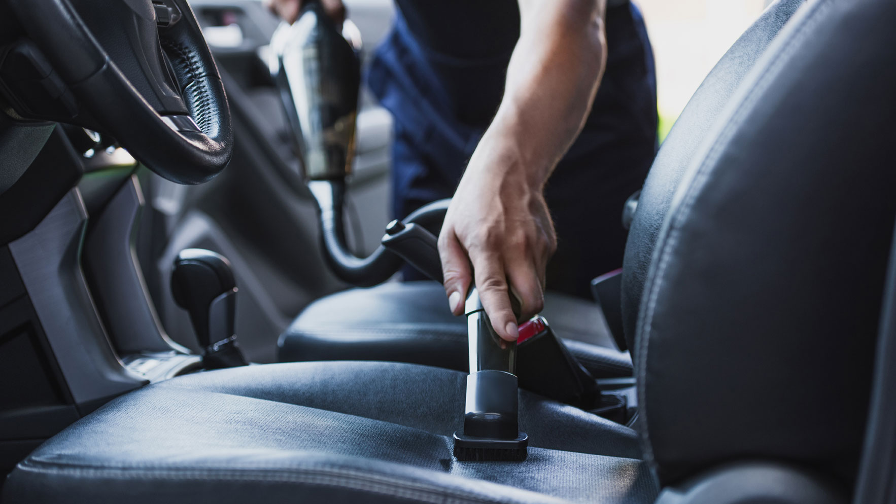 Der Rücksitz eines Autos wird mit einem Sauggerät gereinigt.